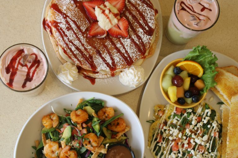 Scramblers Strawberry Short (Pan)Cakes, Asian Shrimp Salad, Scramblers Signature Sausage Frittata, White Mocha Iced Coffee, and Green Tea Iced Matcha displayed on a brunch table.