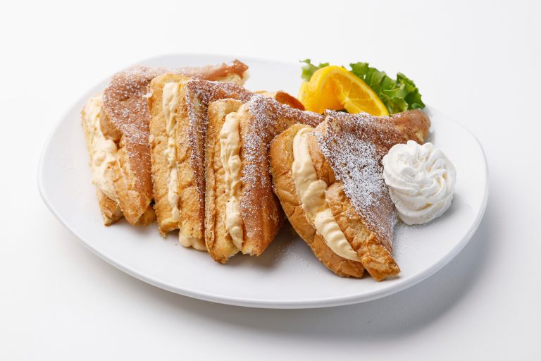 An image of Scramblers' Pumpkin-Stuffed French Toast, featuring four slices with butter and powdered sugar.